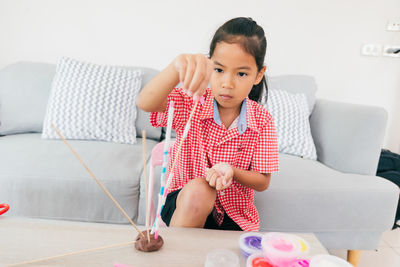 Cute asian child girl playing and creating with play dough and straws. 