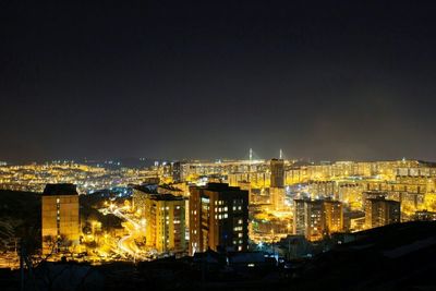 Illuminated cityscape against sky at night