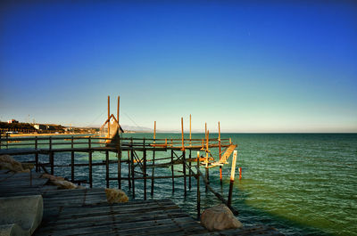 Pier over sea against clear blue sky