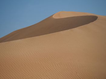 Sand dune in desert against clear sky
