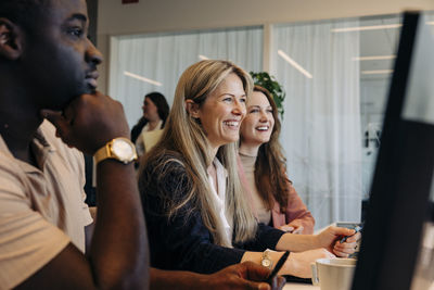 Happy businesswoman discussing with colleagues in coworking office