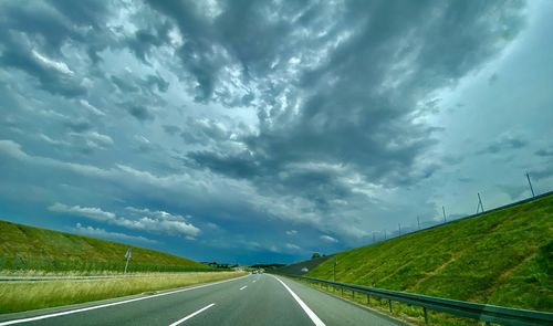 Empty road against cloudy sky