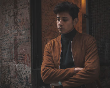 Thoughtful young man looking away against wall