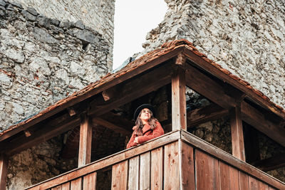 Young woman in winter clothes on wooden balcony of an old medieval castle.