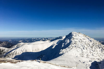 Scenic view of snowcapped mountains against blue sky