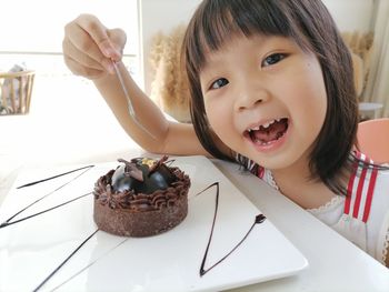 Portrait of smiling girl eating chocolate cake 