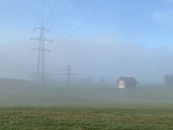 Electricity pylon on field against sky