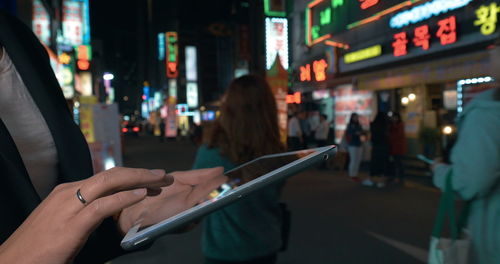 People on illuminated street in city at night