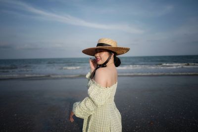 Woman wearing hat while standing on beach