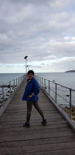 Full length portrait of man standing in sea against sky