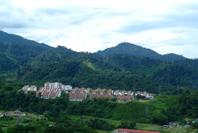 Houses by trees and mountains against sky