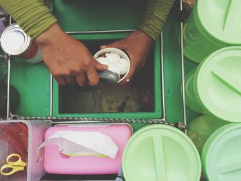 Cropped image of vendor filling coconut ice cream scoops in cup at concession stand