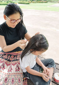 High angle view of mother searching lice from daughter hair outdoors