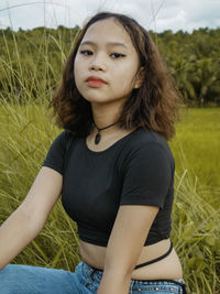 Portrait of beautiful young woman sitting on field