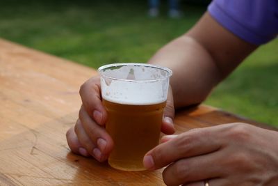 Close-up of hand holding drink on table