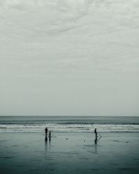 Silhouette people at beach against sky