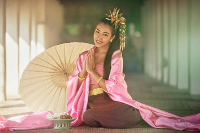 Portrait of smiling girl wearing costume sitting at temple