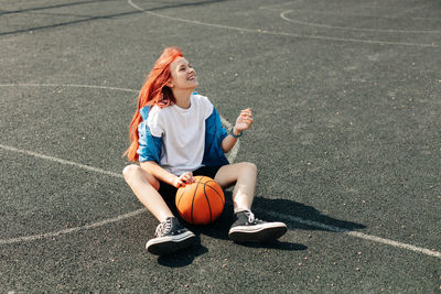 A charming teenage girl with a basketball is resting after a workout. a girl on the sports field. 