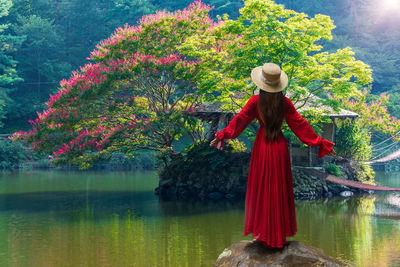 Asian woman stands on a rock looking at flowers on a small island in the south of south korea