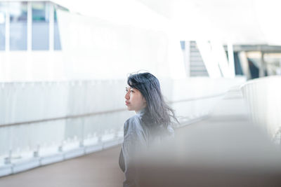 Side view of woman standing against railing