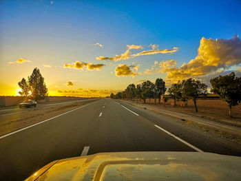 Road by trees against sky seen through car windshield