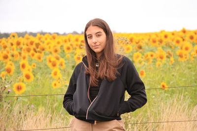Portrait of teenage girl standing against sunflowers in farm