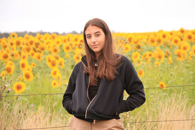 Portrait of beautiful young woman standing on field