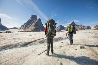 Rear view of people walking on mountain against sky