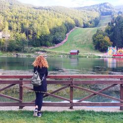 Rear view of woman looking at lake against mountain