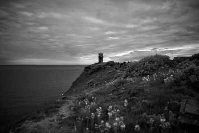 Lighthouse amidst sea and buildings against sky