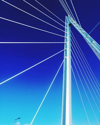 Low angle view of suspension bridge against blue sky