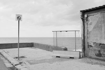 Information sign on beach against sky