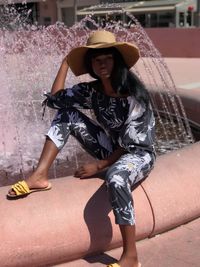 Full length portrait of young woman sitting outdoors