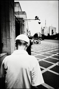 Rear view of man standing on street against buildings