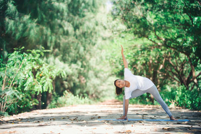 Full length of young woman warming up while exercising at park