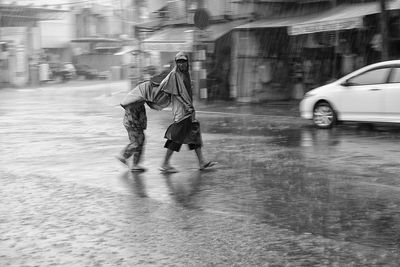 Man trying to keep dry while walking on road during rainy season in city