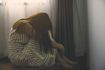 Rear view of woman sitting at home