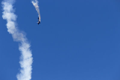 Low angle view of airplane flying against clear blue sky