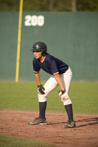 Young baseball player on base path with his hands on his knees