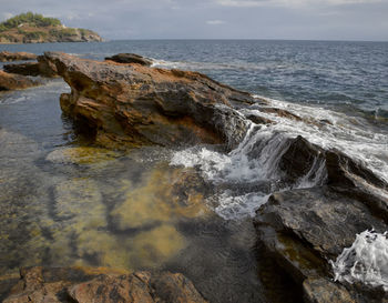 Rock formations at sea shore against sky