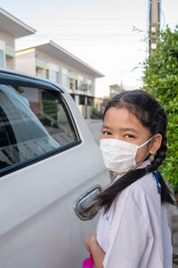 A little asian girl in a uniform wearing masks when going to school to prevent germs