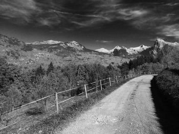 Empty road by mountains against sky