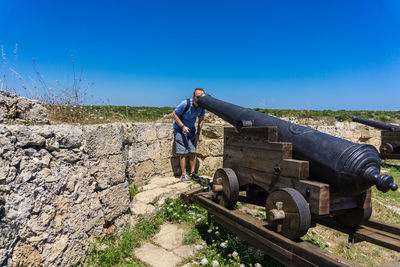 Man looking through cannon on sunny day