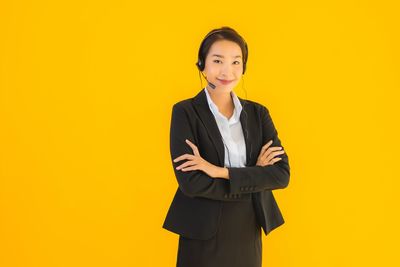 Portrait of a smiling young woman against yellow background