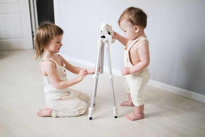 Cute kids siblings understand looking at tripod at home in bright interior