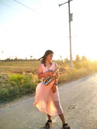 A beautiful girl wearing a dress with a saxophone in a field