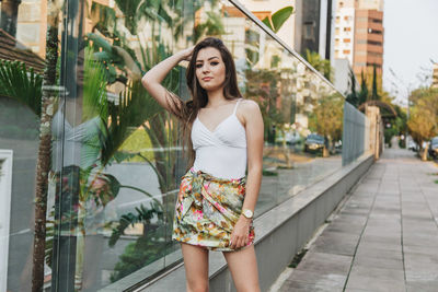Portrait of beautiful young woman standing against building