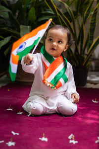 Cute toddler holding indian tricolor flag in traditional cloth with innocent facial expression