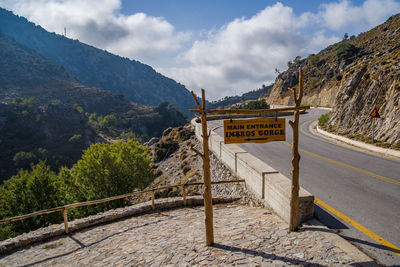 Road sign by mountain against sky