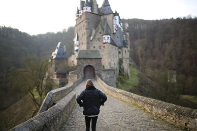 Rear view of man standing by building against mountain